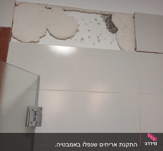 אריחים שבורים על קיר עם חור בתקרה